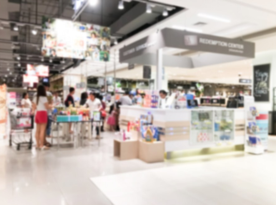 A blurred image of shoppers in a store with various displays, carts filled with items