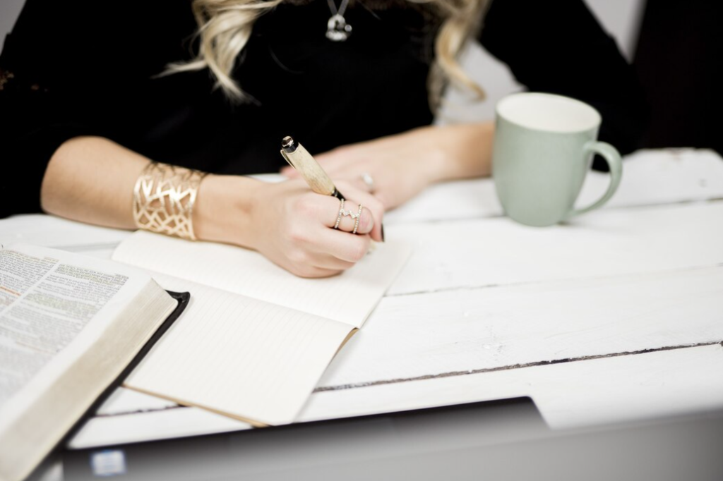 closeup shot of a woman in a black sweater and with a golden ring on her finger  taking notes